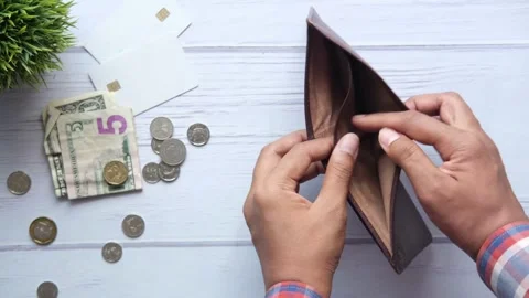 Man hand with empty wallet with pennies small change scattered on table. fiance Stock Footage 336450487