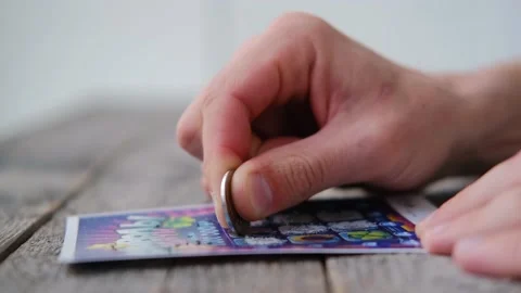 A man is hand erases a protective field in a lottery with a coin Stock Footage 152616952