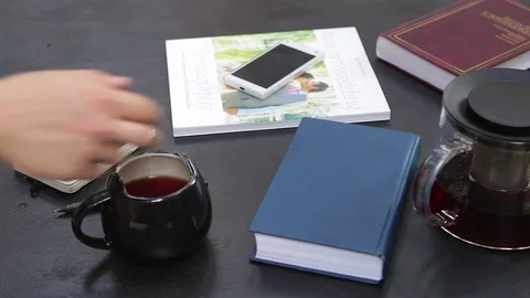 Man hand fill teacup, than taking cup. Teapot, cup, notebook and books around. Stock-Footage 76969543