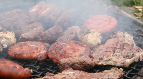 Man hand with a fork flipping the sausages and meat grill Stock Footage 12302182