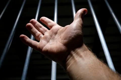 Man hand in front of bars, prison concept Stock Photos