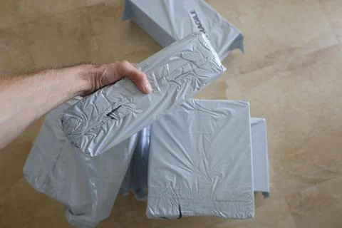 Man hand hold a package in gray posting plastic bag Stock Photos