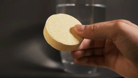 Man hand hold yellow bath salt in the form of tablets for experiments with water Stock Footage 114483045