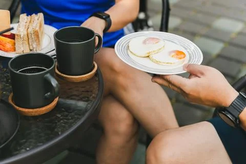 Man hand holding fried eggs for breakfast with coffee on table. Stock Photos