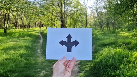 Man hand holding a paper with arrows pointing left, right, and straight directio Stock Footage 307389414