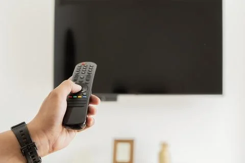 A man hand holding a remote control in front of a smart TV indoors. Banner .. Foto stock