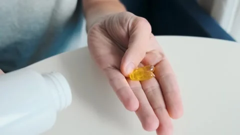 Man hand holding two soft gel capsules with fish oil, omega3 and vitaminD Stock Footage 315861258
