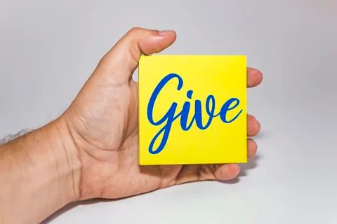 Man hand holding a yellow note paper with the text give against white backgro Stock Photos