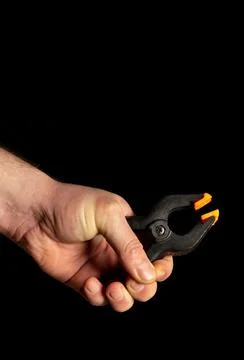 Man hand holds plastic spring clamps on black isolated background Stock Photos