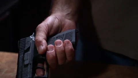 Man hand inserts charged clip into gun Stock Footage 116502709