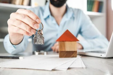 Man hand key with house model on desk Stock Photos
