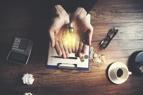 Man hand light bulb or idea and stationary on table Stock Photos