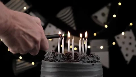 Man hand lights silver candles on black birthday cake. fun holidays. close-up. Video stock 278600071