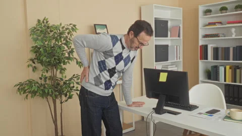 Man with hand on lower back for backache leaning on computer monitor in bui.. Stock Footage 337442183