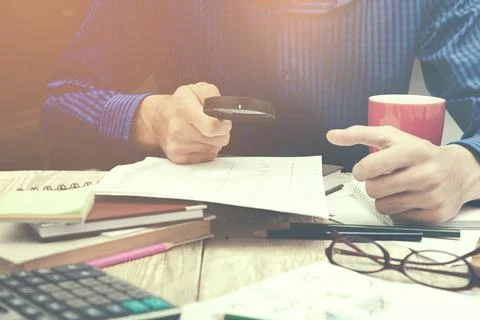 Man hand magnifier  on working table Stock Photos