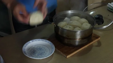 Man hand moving hot steamed buns from the pot to a plate Stock Footage 47698242