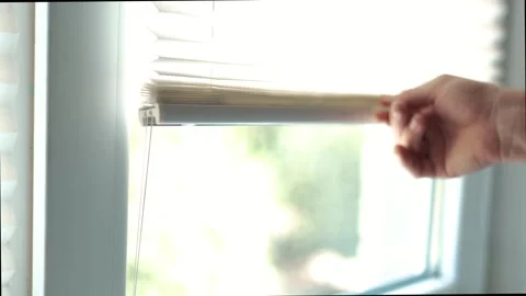 Man hand opening white pleated blinds on a plastic window on a sunny day 스톡 동영상 340159342