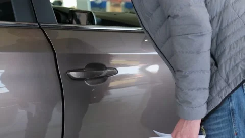 A man is hand opens a car door in a car dealership. Stock Footage 149593584