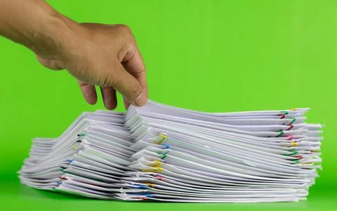 Man hand picking up paper in stack documents on green background, paper savin Stock Photos