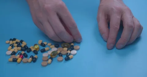 Man hand with pills, tablets, vitamins, drugs, capsules isolated on blue Stock Footage 126180792