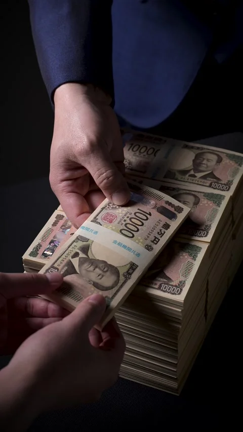 Man hand placing a bundle of new Japanese yen bills on a stack Stock Footage 336765978