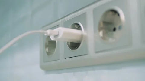 Man hand plug white phone charger adapter into wall socket Stock Footage 141078055