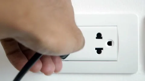 Man hand plugging and unplugging electronic into electric wall socket. Stock Footage 50347889