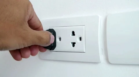 Man hand plugging and unplugging electronic into electric wall socket. Stock Footage 50348027