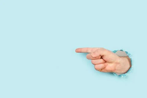 Man hand with pointing finger to the left through a hole Foto stock