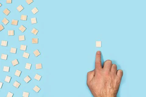 Man hand pointing a single square wooden block on a light blue background Stock Photos