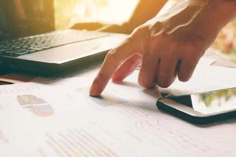Man hand pointing on summary report and thinking about cost at home office. Stock Photos