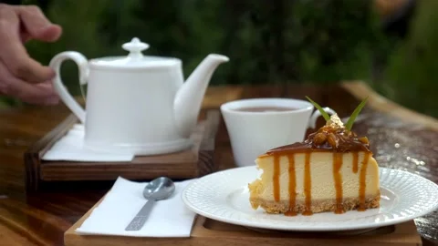 Man hand pouring hot tea in tea cup. Piece of delicious fresh cake in cafe Vídeos de archivo 167275611