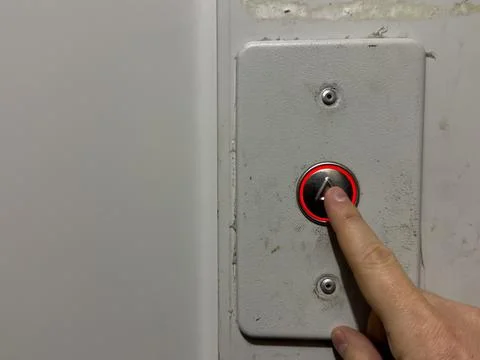 A man hand presses the elevator call button in an old house, silver elevator Foto stock