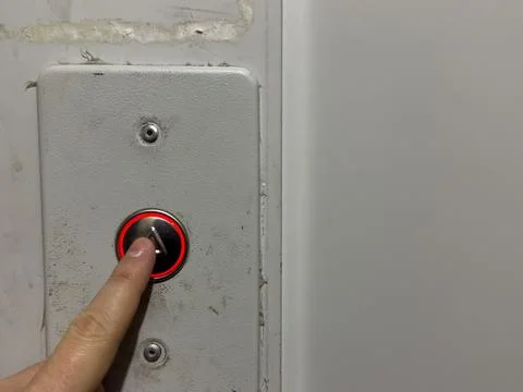 A man hand presses the elevator call button in an old house, silver elevator Stock Photos