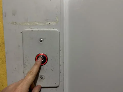 A man hand presses the elevator call button in an old house, silver elevator Foto stock