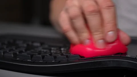 Man hand pressing pink cleaning slime on black keyboard to remove dust and Vídeo Stock 342758868