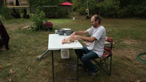 Man hand processing or gutting freshly butchered chicken in his back yard Stock Footage 250951516