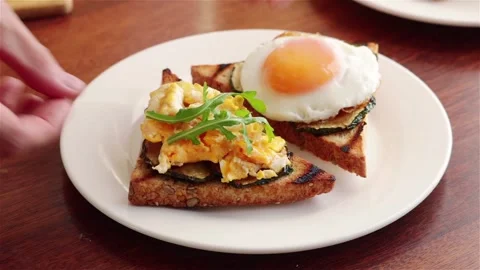 Man hand put arugula leaves on healthy sandwich with fried egg grilled zucchini Stock Footage 241127327