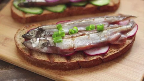 Man hand put chopped chives on sandwich with salted capelin sardines radish Stock Footage 244968647