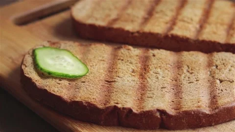 Man hand put fresh cucumber slices on grilled bread close up Stock Footage 119422805