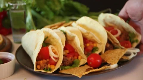 Man hand put a Mexican tacos with chicken meat, beans, tomatoes and corn. Stock Footage 130807837
