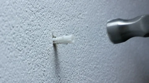 Man hand put  plastic plug , wall anchors into the concrete cement white wall Stock Footage 89729886