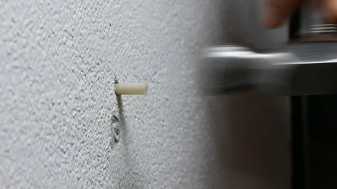 Man hand put  plastic plug , wall anchors into the concrete cement white wall Stock Footage 89730649