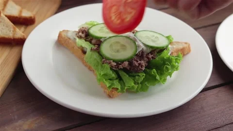 Man hand put tomatoes slices on sandwich with tuna cucumber lettuce cream cheese Stock Footage 115501294