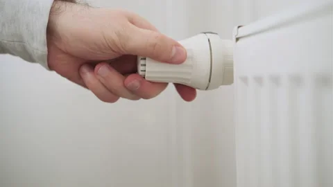 Man hand regulates temperature knob of heating radiator to reduce heating costs. 動画素材 182489230
