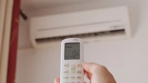 Man hand with remote control turn off air conditioning. Stockbeeldmateriaal 157789559