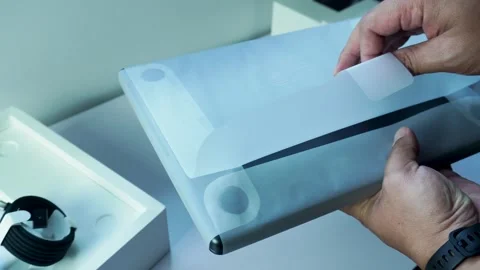 Man Hand Removing White Protective Cover From New Apple M5 14 Inch Macbook pro Stockbeeldmateriaal 334645176