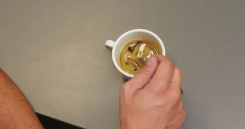 A man hand with a ring stir up the coffee in with cup with a teaspoon Stock Footage 261997179