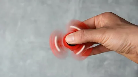 Man hand rotating red plastic fidget spinner on marble background. Anti stres Video stock 188437071