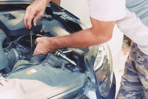 Man hand with screwdriver checking car engine Stock Photos